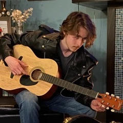 Picture of Luke Jackson in a leather jacket with an Accoustic guitar